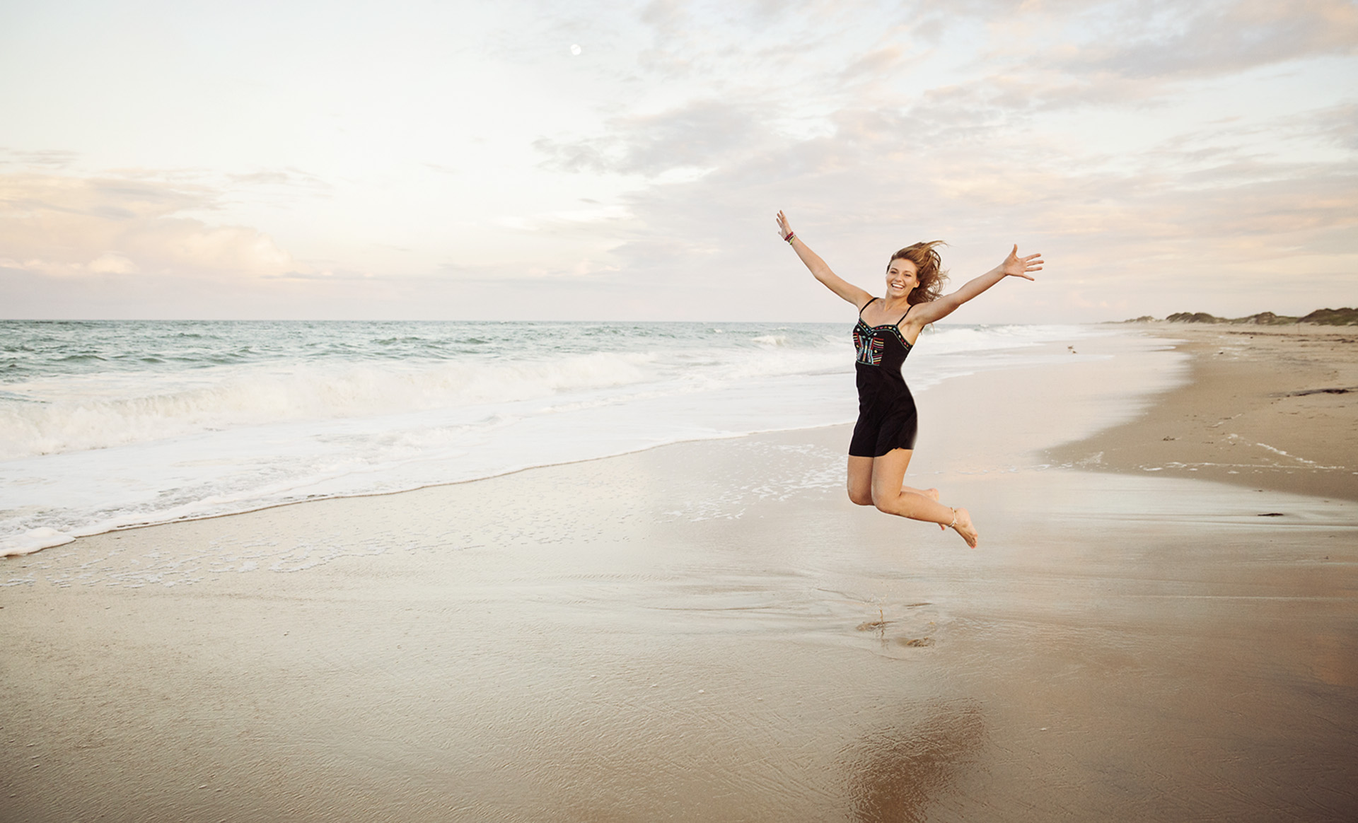 Senior girl jumping by the ocean