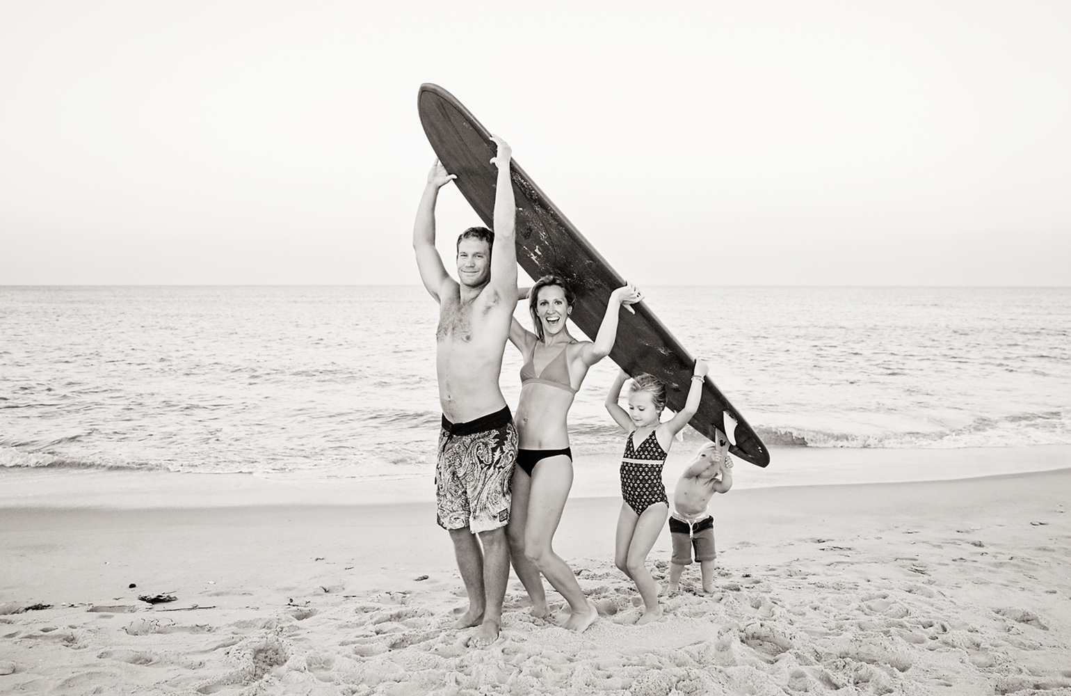 Local Outer Banks family holding up a surfboard