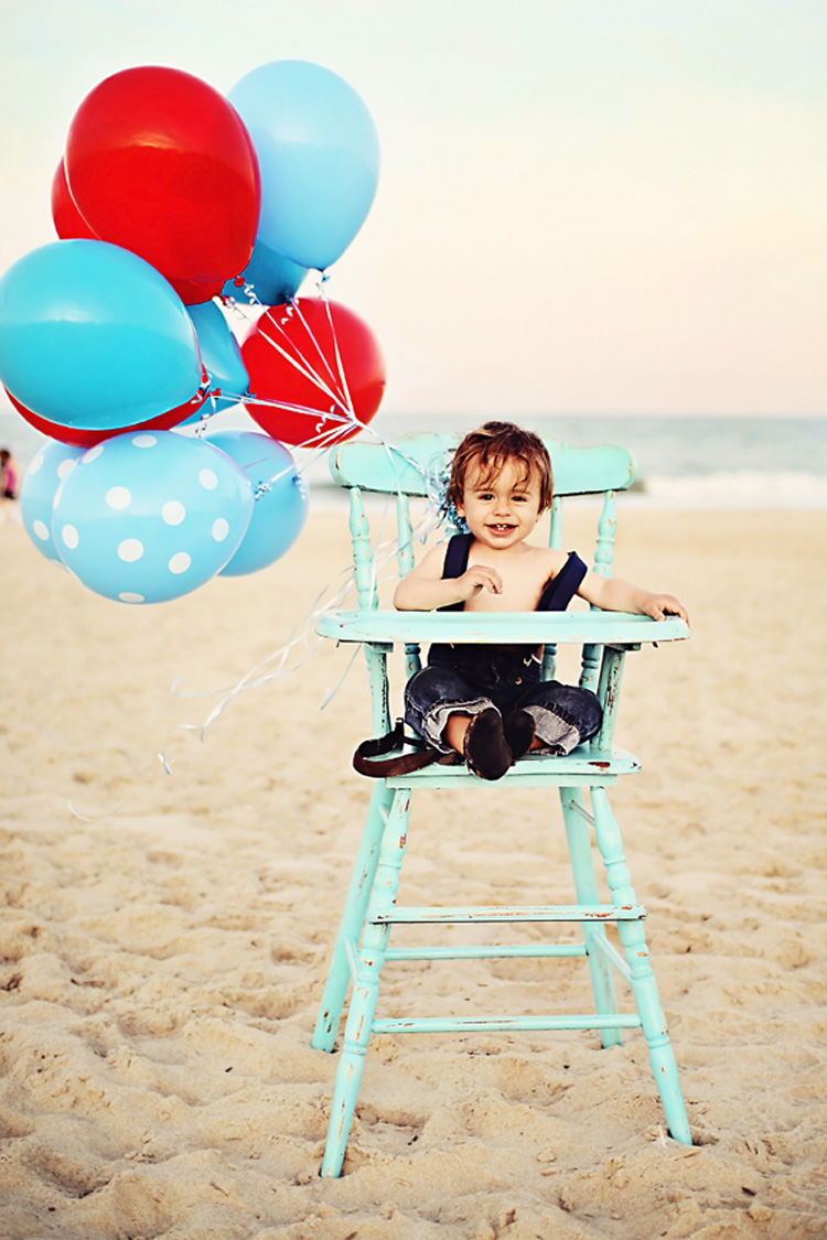 One year old with balloons in a high chair at the beach in NC