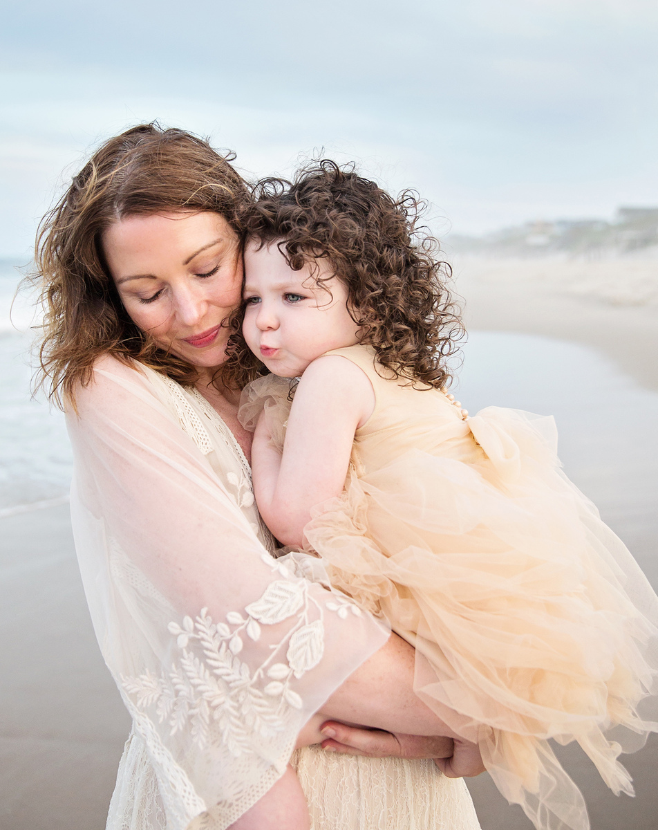 Photo of child and mother snuggling on the beach